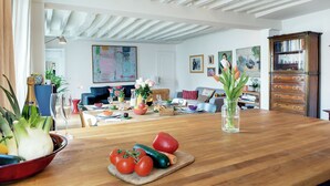 Uma sala de estar ampla com uma mesa de jantar de madeira, um sofá e uma estante de livros.