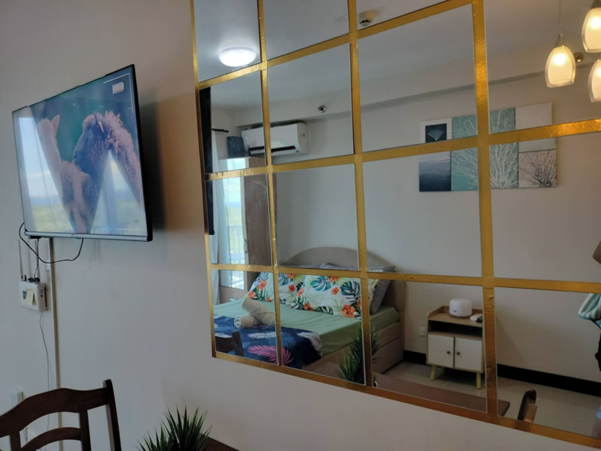 A room with a bed, a desk, a chair, a TV, and a mirror.