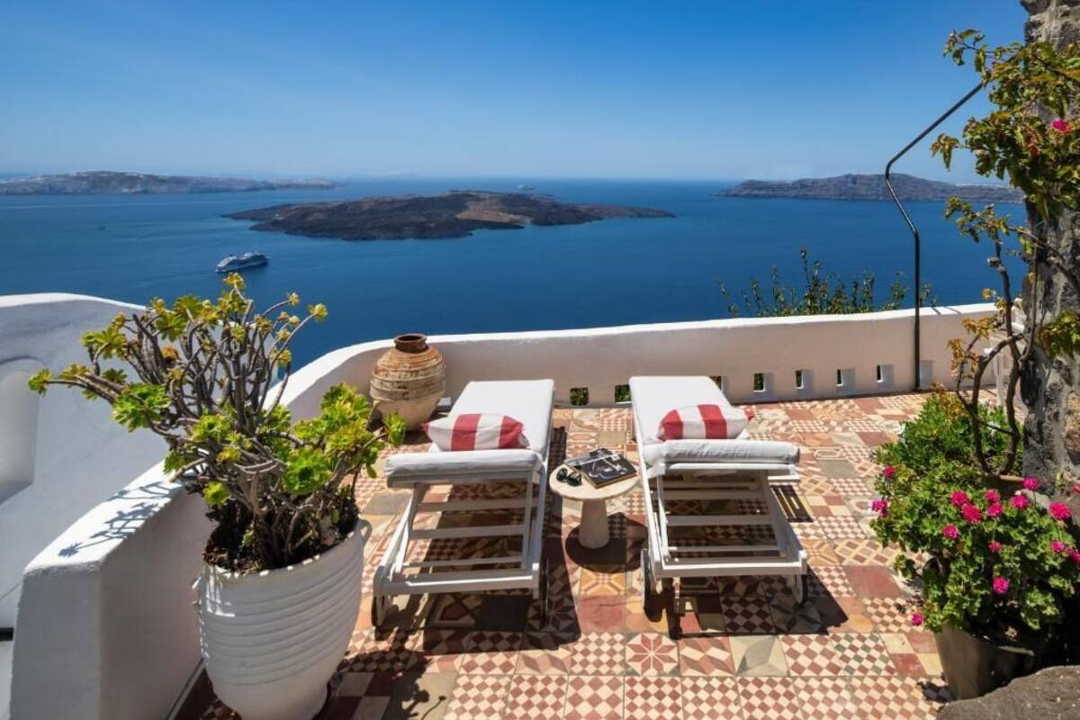Une terrasse avec deux chaises longues, un pot de fleurs et une vue sur la mer.