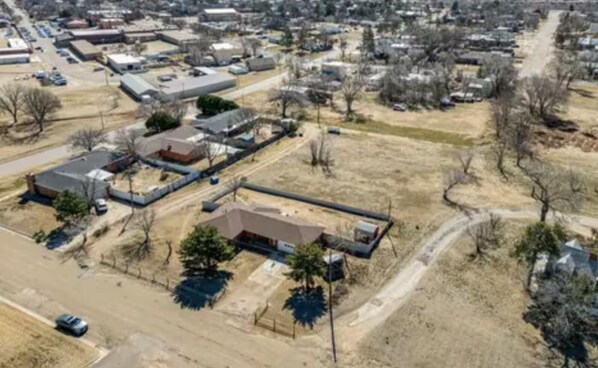 An aerial view of a residential area with houses, a parking lot, and a building with a flat roof.