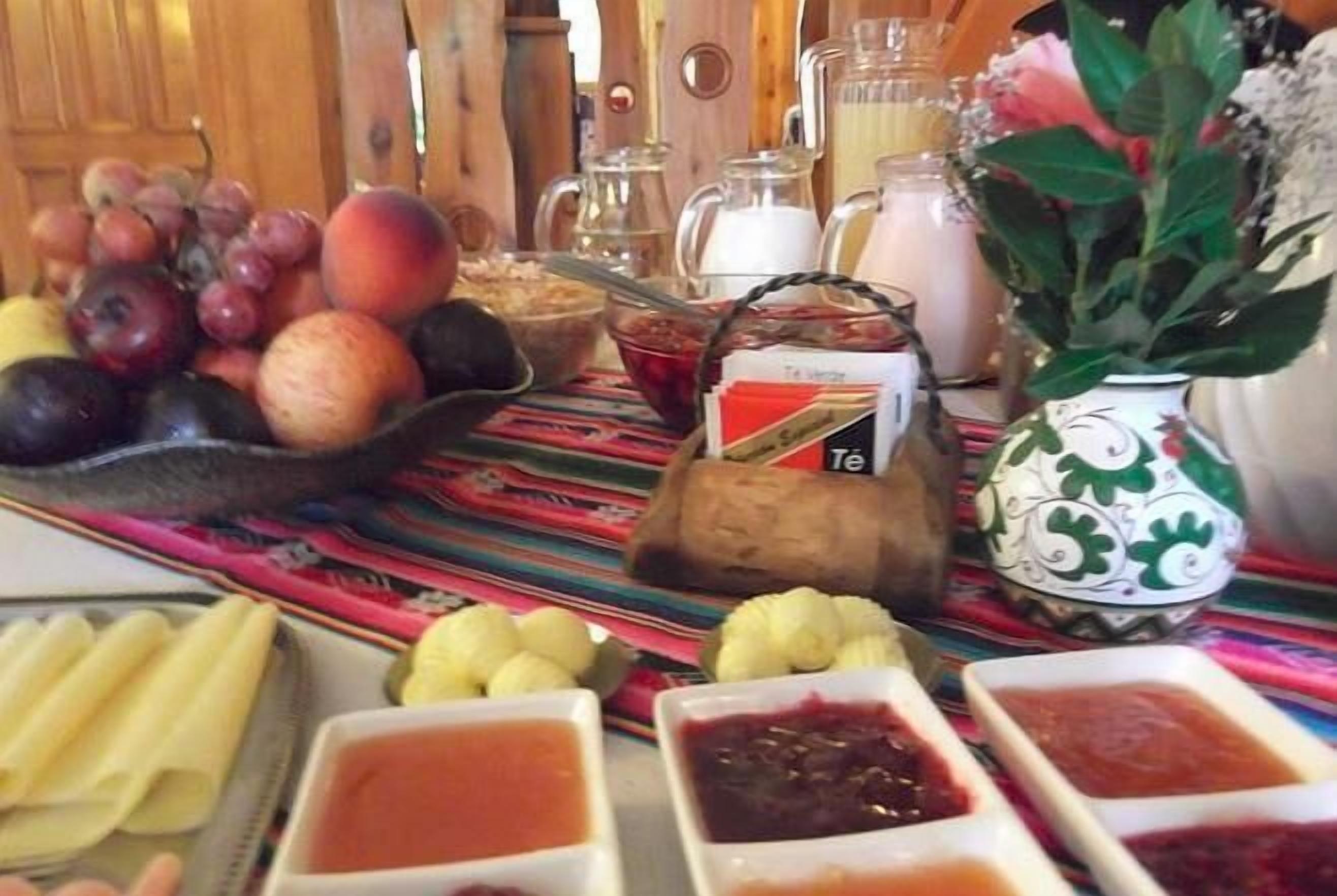 A table with various fruits, condiments, and a teapot.