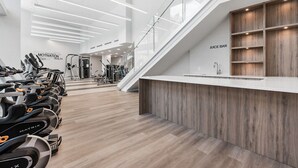 Ein modernes Fitnessstudio mit Trainingsgeräten, einer Juice Bar und einer Treppe.