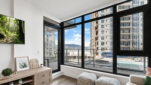 Ein modernes Wohnzimmer mit großem Fenster, Holzschrank und Sofa.