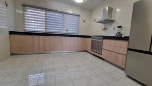 A kitchen with a built-in oven, a sink, and a window with blinds.