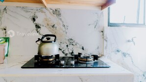 Cozinha com fogão a gás, chaleira e painel de parede em mármore.