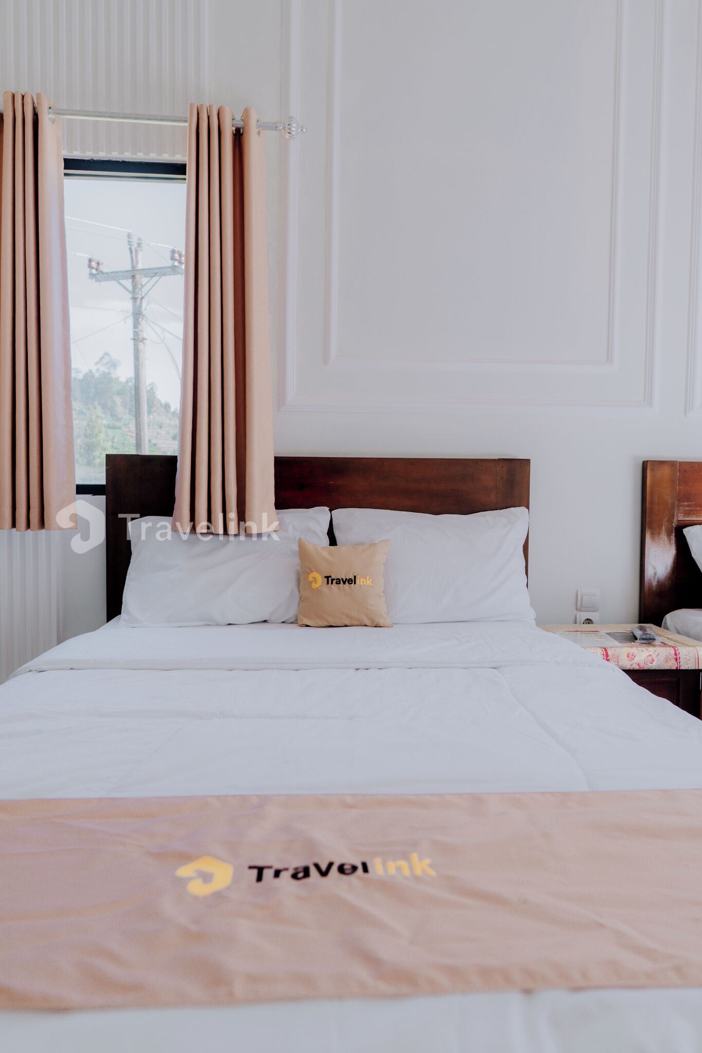 A hotel room with a neatly made bed, a wooden headboard, and a window with curtains.