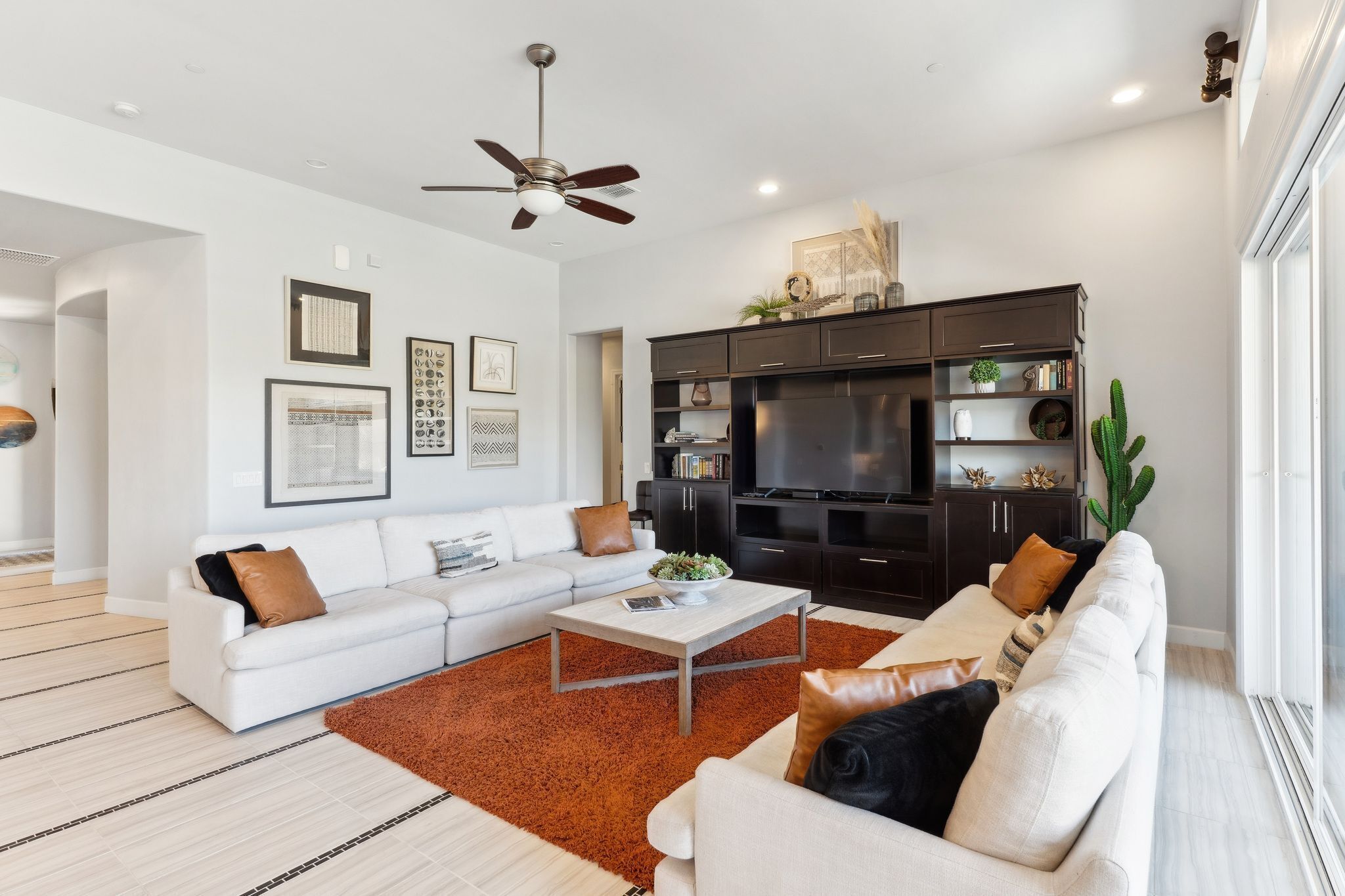 A modern living room with a white sofa, a coffee table, and a dark entertainment unit.