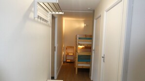 A narrow hallway with a bunk bed and a white table.