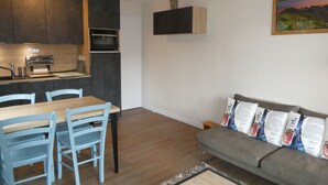 A compact living space with a kitchen, dining area, and a sofa with patterned cushions.