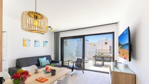 A modern living room with a dining area, large windows, and a view of the cityscape.