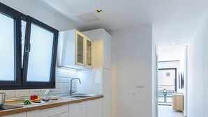 A modern kitchen with white cabinets, a wooden countertop, and a large window.