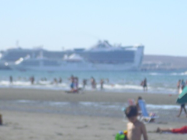A beach with people and boats in the background.