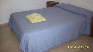 A single bed with a blue bedspread and a folded yellow towel on it. - Hostel Viajeros (Puerto Madryn)