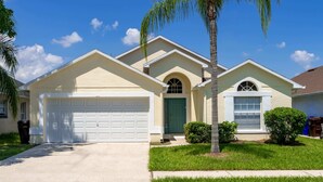 A single-story house with a garage, a green door, and a small lawn.