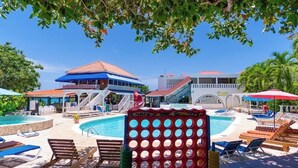 A pool area with lounge chairs, a slide, and a building with a red roof. - Welcome to Ocean's Tropical Escape!
Beach front, beach access 1-bedroom, 4 bed. (Runaway Bay)