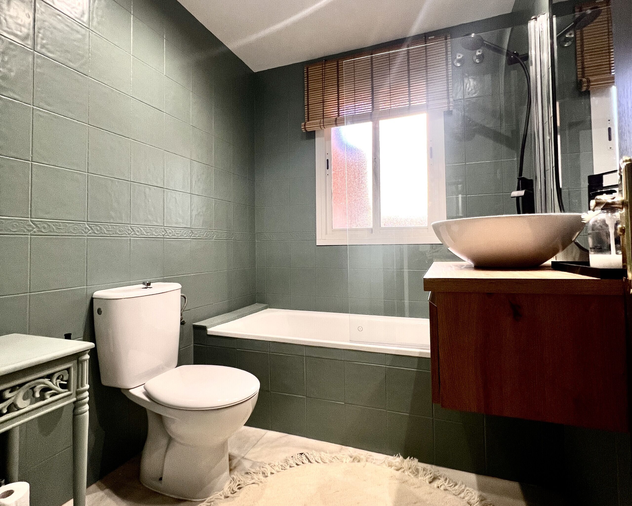 Un baño con inodoro, bañera y un espejo grande sobre el lavamanos.