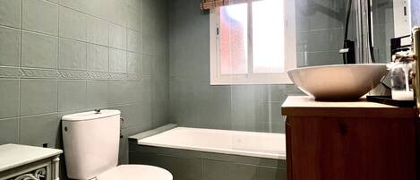 Un baño con inodoro, bañera y un espejo grande sobre el lavamanos.
