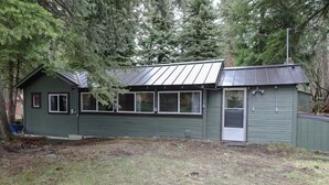 A small, single-story building with a metal roof, a garage door, and a door.