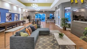 A modern hotel lobby with a grey sofa, a coffee table, and a reception desk. - Landing | Beautiful 1BD, Pool, Gym (Phoenix)