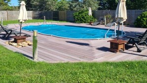 Un jardin avec une piscine, des chaises longues et des parasols.