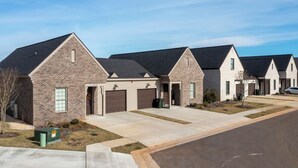 A row of modern single-family homes with brick exteriors and dark roofs, featuring attached garages and a well-maintained lawn. - Landing | Chic 2BD, Clubhouse, Gym (Athens)