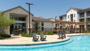 A swimming pool with lounge chairs and a pergola, surrounded by apartment buildings. - Landing | Chic 1BD, Gym, Pool (Manor)