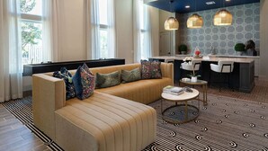 A modern living room with a sofa, a coffee table, and a kitchen area with a bar. - Landing | Chic 1BD, Gym, Pool (Manor)
