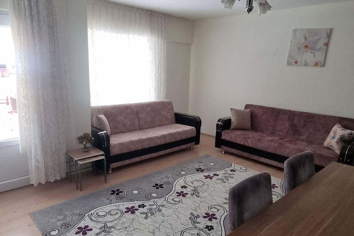 A living room with two sofas, a dining table, and a chandelier.