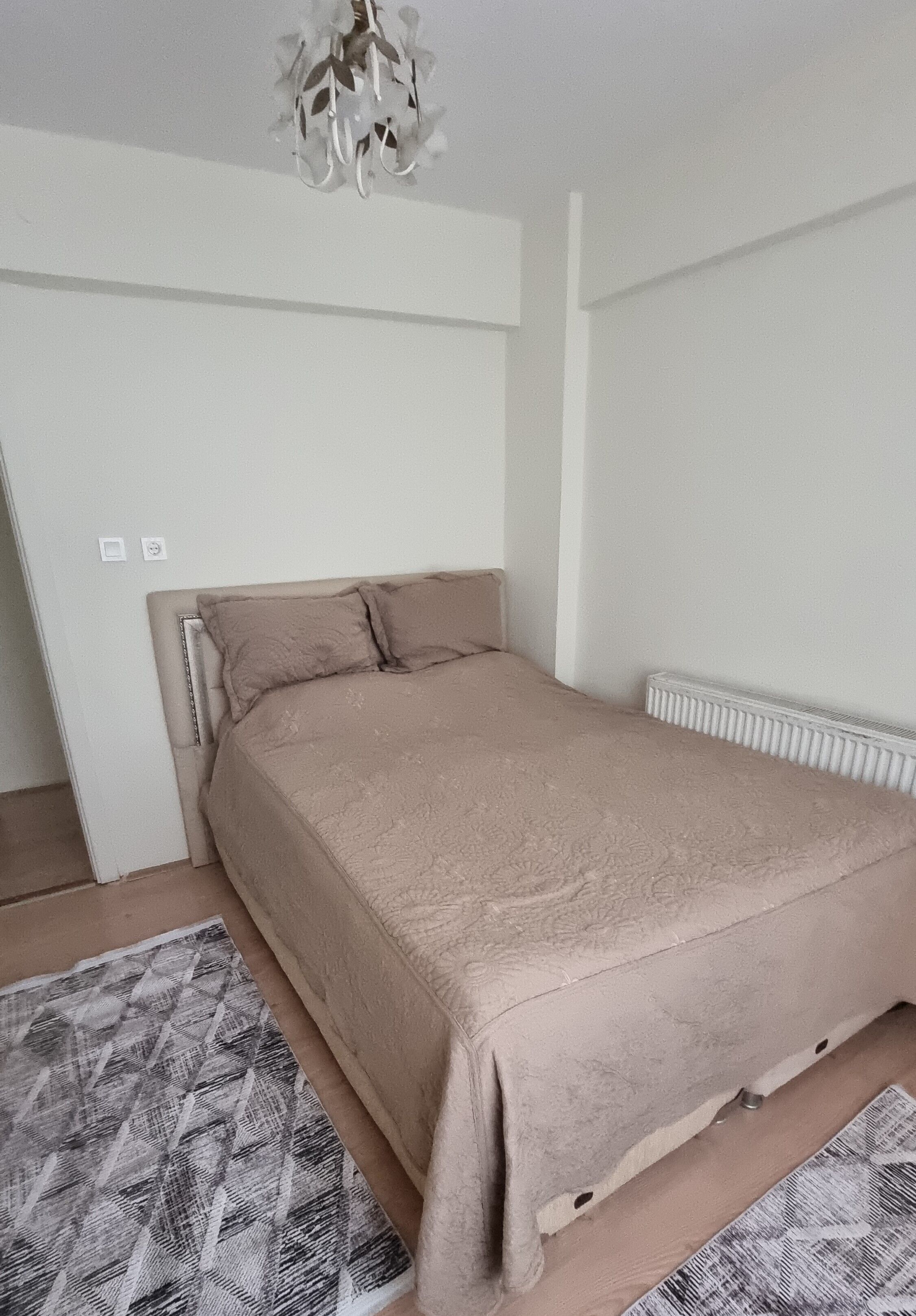Ein Schlafzimmer mit einem Bett, einem Heizkörper und einem gemusterten Teppich.