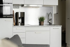 Une petite cuisine équipée d’une machine à café, d’un évier et d’une petite plante.
