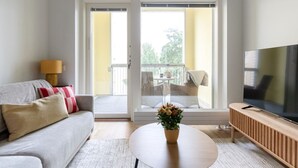 A living room with a sofa, a TV, a coffee table, and a balcony with outdoor furniture. - Come in! `Vapari 2` Astonishing studio in stadium! (Tampere)