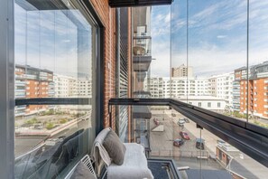 A high-rise apartment with a view of surrounding buildings and a parking area below.