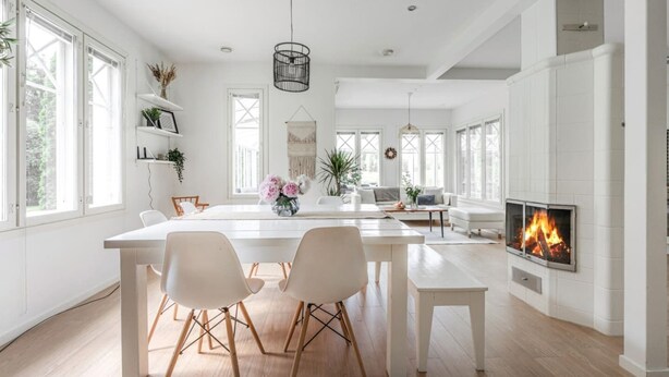 Una cocina amplia con una isla grande, armarios blancos y una chimenea empotrada.