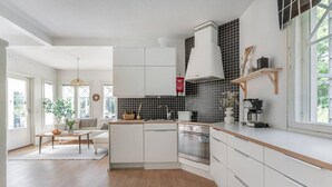 Una cocina moderna con armarios blancos, horno empotrado y salpicadero de azulejos negros.