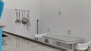 A kitchen with a marble countertop, a white chair, and hanging kitchen utensils. - Few steps from Ipanema & Arpoador Beaches (Ipanema)