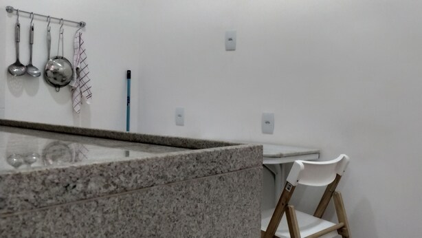 A kitchen with granite countertops, a white chair, and hanging kitchen utensils. - Few steps from Ipanema & Arpoador Beaches (Ipanema)