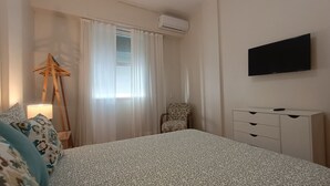 A hotel room with a bed, a chair, a desk, a TV, and an air conditioning unit. - Few steps from Ipanema & Arpoador Beaches (Ipanema)