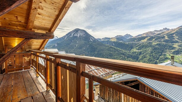 A wooden balcony with a view of a mountain.