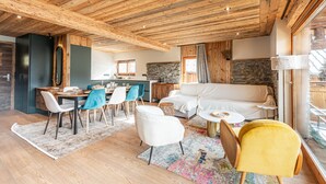 A modern interior with a wooden ceiling, a dining area with chairs and a table, a sofa, and a large window with a view.