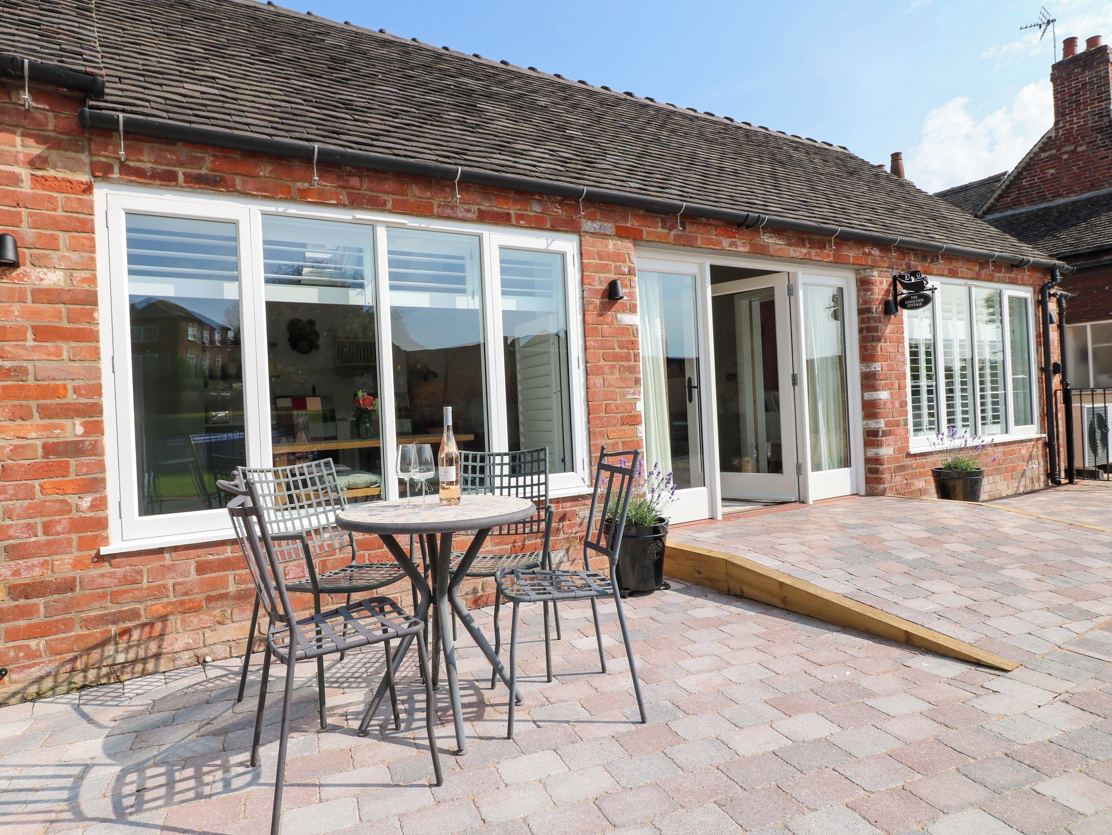 A brick building with large windows and a patio area with metal chairs and a table.