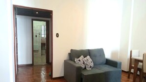 A living room with a grey sofa, patterned cushions, a wooden floor, and a dining area with a table and chairs. - Charming apartment in enjoyable Flamengo Rio de Janeiro near Park Aterro (Flamengo Rio de Janeiro)