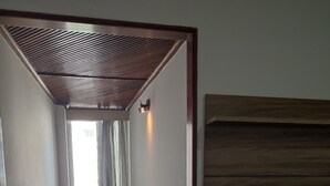 A compact room with a wooden ceiling, a small table, a TV mounted on a wooden shelf, and a window with curtains. - Charming apartment in enjoyable Flamengo Rio de Janeiro near Park Aterro (Flamengo Rio de Janeiro)
