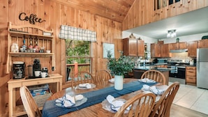A wooden cabin interior with a dining area, kitchen, and coffee station. - Mountainside retreat in the Smokies!  6 miles to The Island. Sleeps 8. (Sevierville)