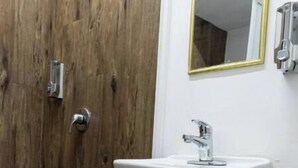 A bathroom with a wooden door, a white sink with a mirror, and a towel rack.