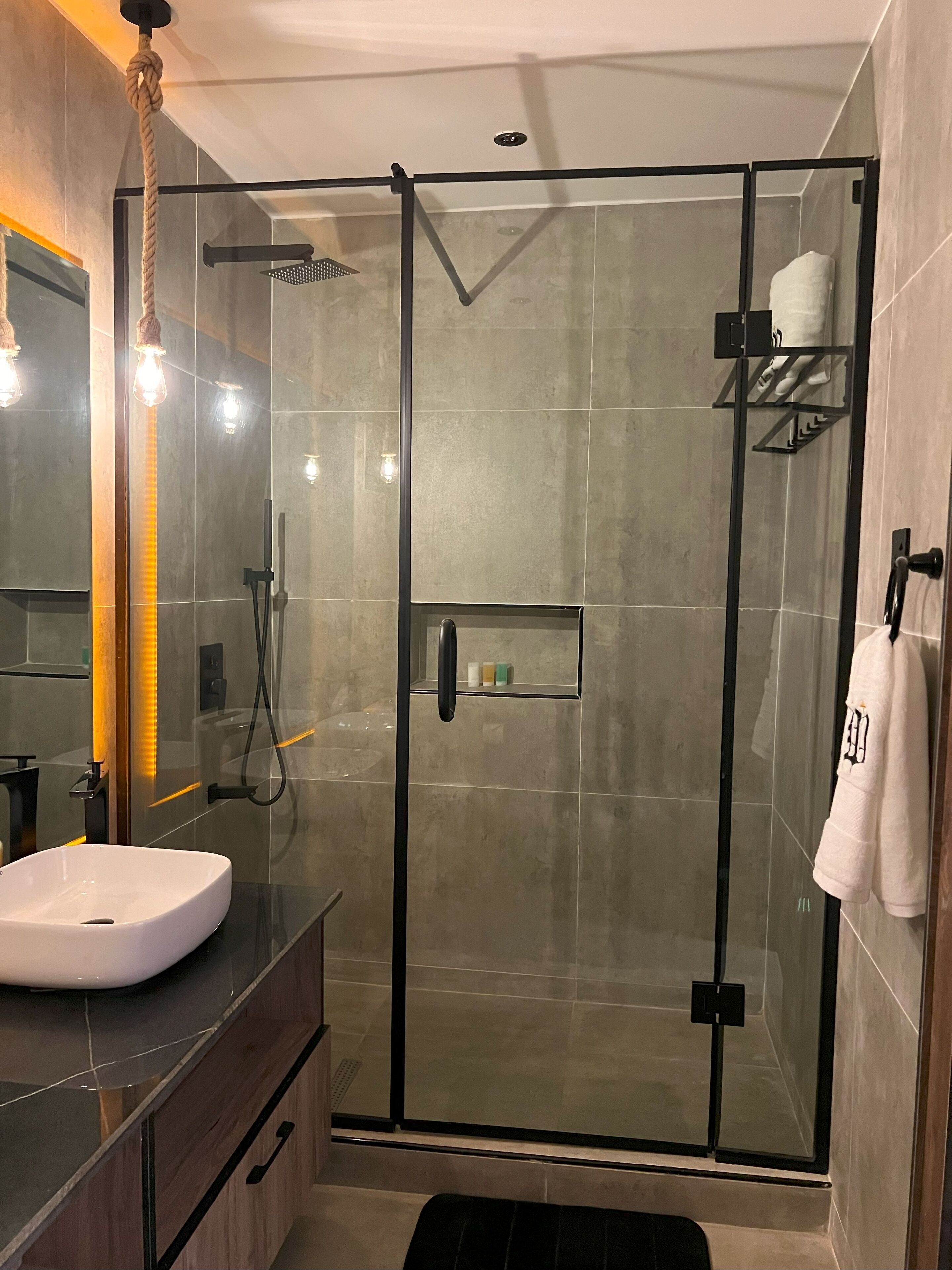 A modern bathroom with a glass-enclosed shower, a white sink, and a towel rack.