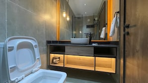 A modern bathroom with a toilet, sink, and wooden vanity. - The Westbury Inn Hotels and Apartments (Abuja)