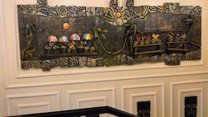 A wall with a large, abstract mural featuring a variety of objects and patterns. - The Westbury Inn Hotels and Apartments (Abuja)