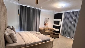 Ein modernes Schlafzimmer mit einem großen Bett, einer Couch, einem Fernseher und einem kleinen Tisch.