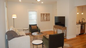 Ein modernes Wohnzimmer mit einer Couch, Sesseln, einem Couchtisch und einem Fernseher.
