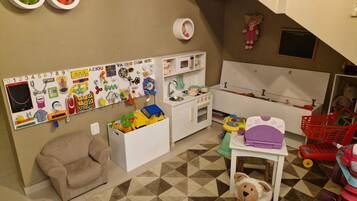 Um espaço de brincar com uma cozinha de brinquedo, brinquedos e um tapete estampado.